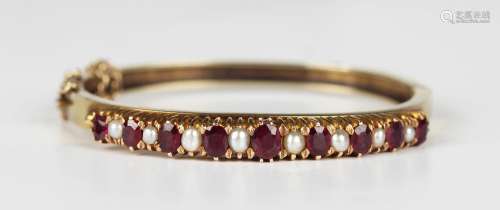 A gold, ruby, pearl and half-pearl set oval bangle, mounted ...
