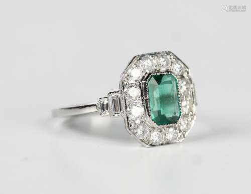 A platinum, emerald and diamond cluster ring, collet set wit...