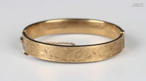 A 9ct gold oval hinged bangle, the front with scroll engrave...