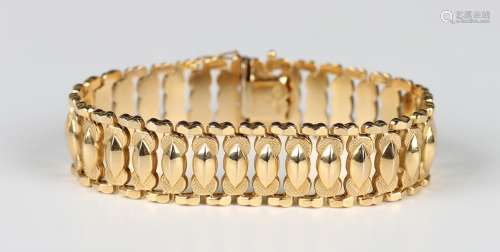 A gold bracelet in a wide tapered oval and partly textured l...