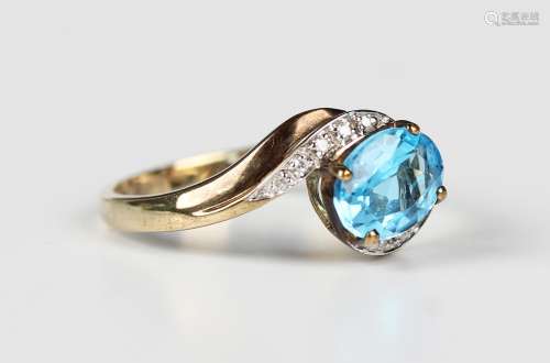 A 9ct gold ring, claw set with an oval cut blue topaz betwee...