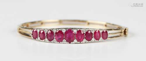 A gold, ruby and diamond oval hinged bangle, the front mount...