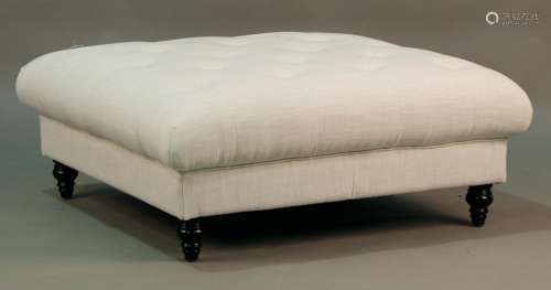 A modern footstool, upholstered in buttoned white fabric, on...