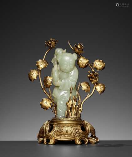 A CELADON JADE FIGURE OF A BOY MOUNTED ON A GILT BRONZE STAN...