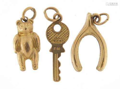 Three 9ct gold charms of a wishbone, teddy bear and key, the...
