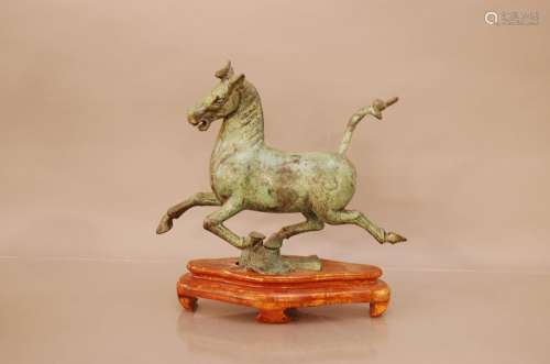A cast Chinese bronze of a prancing horse 33cm high on a woo...