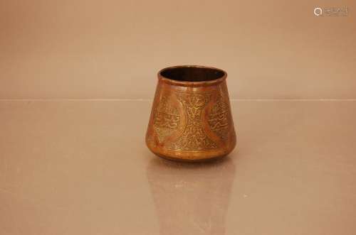 A Middle Eastern brass pot, Arabic writing and scrolling dec...