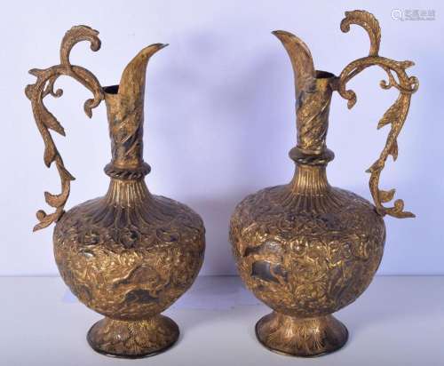 A large pair of South East Asian repoussé gilded metal ewers...