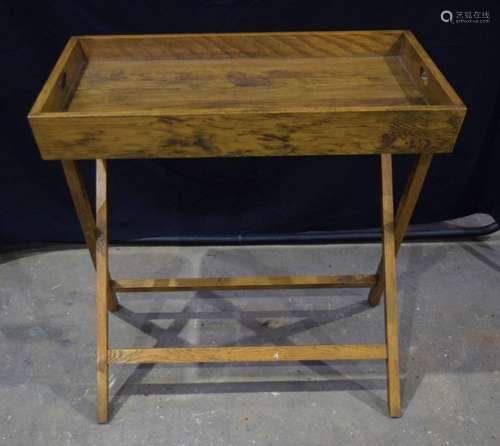 A contemporary wooden butlers tray on a X frame stand possib...