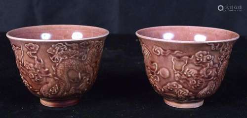 A pair of Chinese tea bowls decorated in relief with a drago...