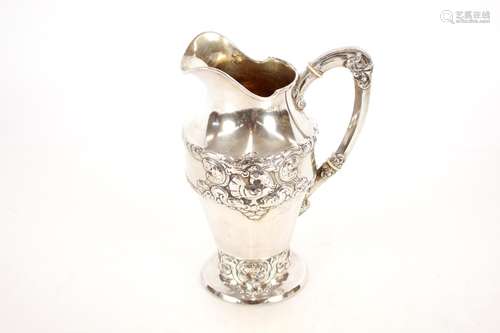 A continental white metal ewer,with raised foliate decoratio...