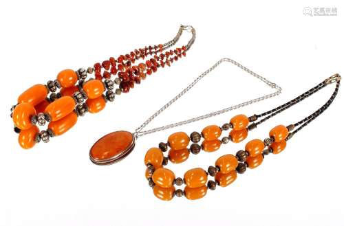 An amber pendant, on fine link white metal chain; and two bu...