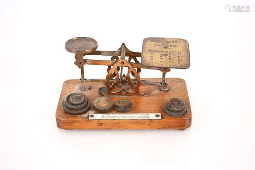 A set of oak and brass postal scales and weights