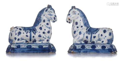 A pair of Dutch Delft blue and white figures of recumbent ci...