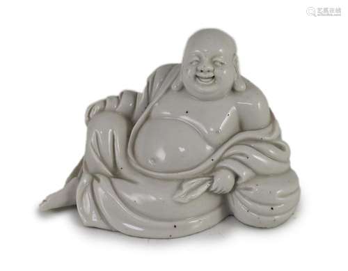 A Chinese blanc-de-chine reclining figure of a smiling Budai...