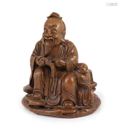 A Chinese carved bamboo figure of a seated sage reading a bo...