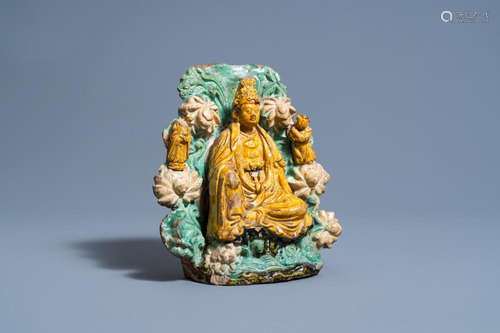 A CHINESE SANCAI GLAZED EARTHENWARE GROUP OF A SEATED BUDDHA...