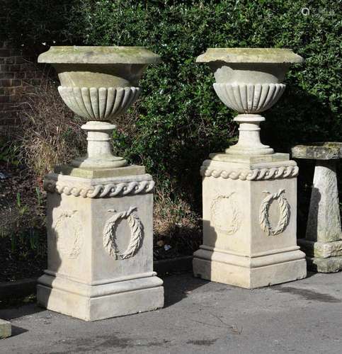 A LARGE PAIR OF COTSWOLD STONE VASES ON PEDESTALS, VASES CIR...