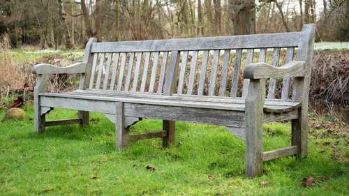 A LARGE WEATHERED HARDWOOD GARDEN BENCH, IN THE MANNER OF R....