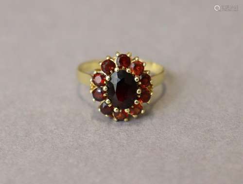 A garnet cluster ring, the central oval stone set within a b...