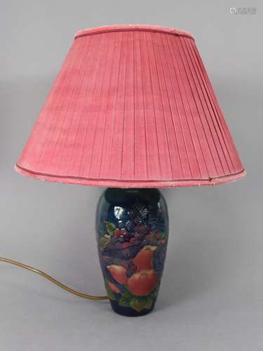 A Moorcroft pottery table lamp decorated with birds, apples,...