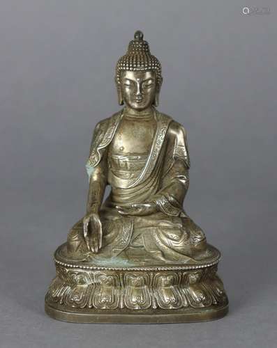 An oriental white metal figure of a Buddhistic deity, seated...