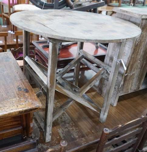 A French provincial pine circular table on folding underfram...