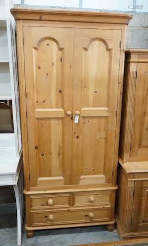 A modern narrow pine wardrobe, the base fitted with three dr...