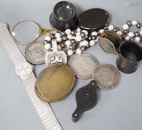 A collection of coins, magnifying loupes, cultured pearl nec...