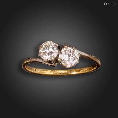 A two-stone diamond crossover ring, set with two round brill...