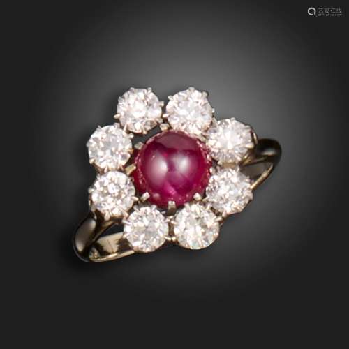 A ruby and diamond cluster ring, the ruby cabochon is set wi...