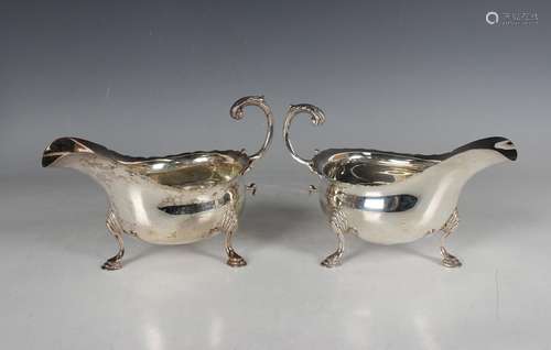 A pair of Edwardian silver sauceboats, each with a foliate c...