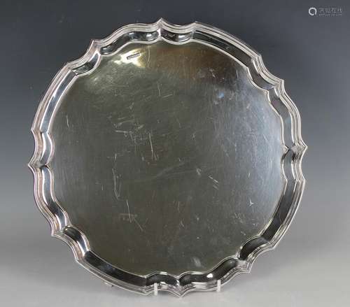 A George V silver circular salver with raised shaped rim, on...