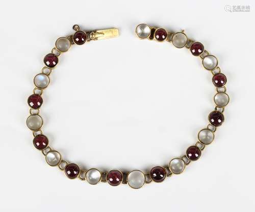 A gold, moonstone and cabochon garnet bracelet, mounted with...