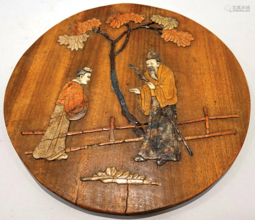A wooden hanging decor with inlaid gems and carved figures.