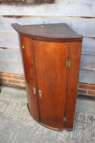 A Georgian mahogany bowfront corner hanging cupboard enclose...