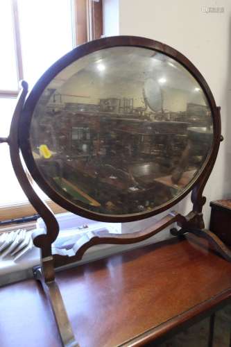 An Edwardian mahogany oval swing frame toilet mirror, on ske...