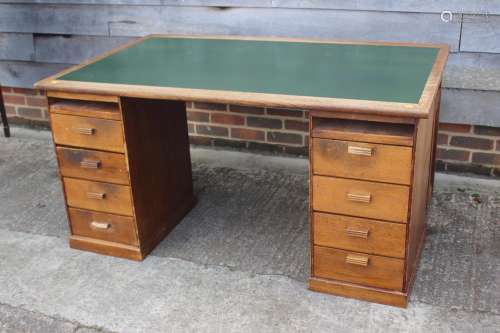 A 1920s oak desk, fitted eight drawers and green leatherette...