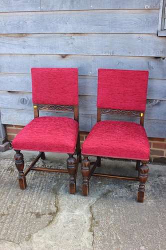 A pair of oak framed dining chairs, upholstered in a red fab...