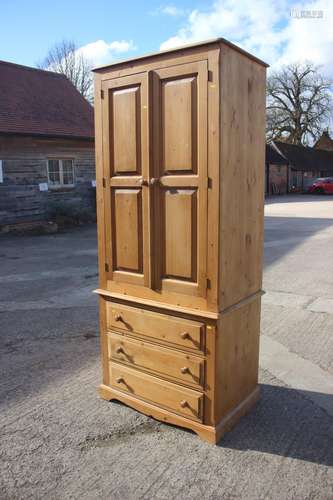 A waxed pine wardrobe, the upper section enclosed two panell...