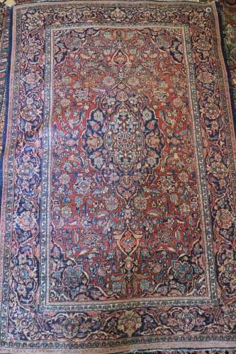 An antique Persian rug with blue central medallion on a rust...