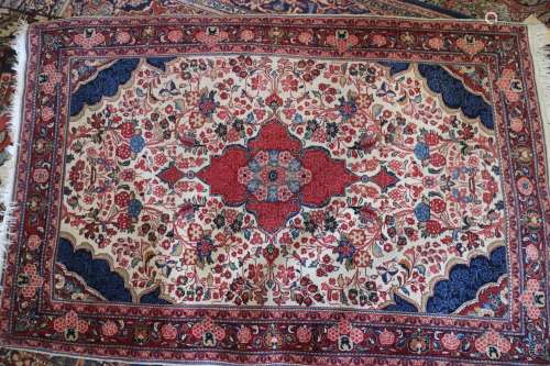 A Kashan rug with red central medallion on a floral scroll a...