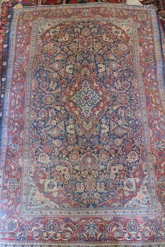 An antique Persian rug with central medallion on a blue flor...