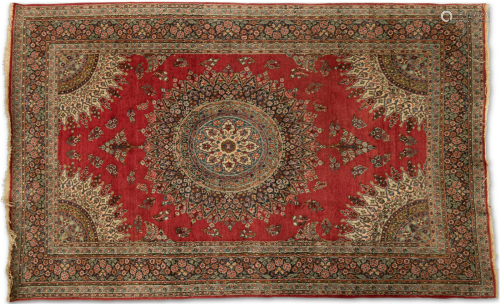 A PERSIAN RUG, hand-knotted, the deep red field with a highl...