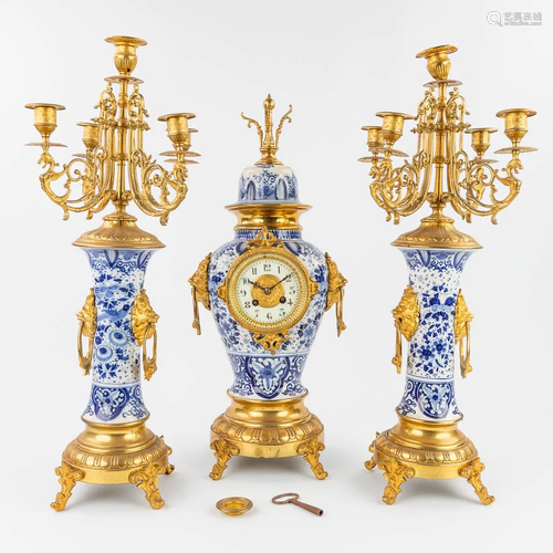 A three-piece mantle clock with candelabra made of Delft...