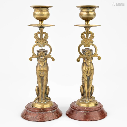 A pair of candlesticks with lion figurines mounted on a red ...