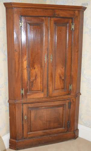 A George III oak corner cupboard, the moulded cornice above ...