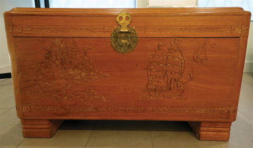 A large camphor wooden box with carving of sailboats.