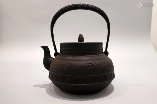 An iron kettle with maple leaf pattern design.