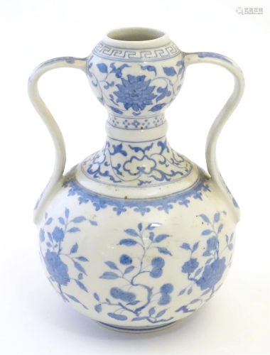 An Oriental blue and white double gourd vase with twin handl...